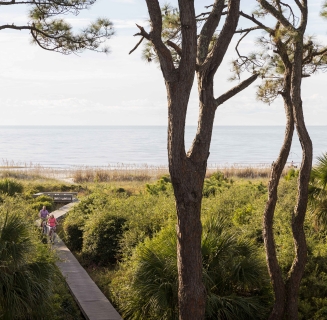 people walking on boardwalk away from beach
