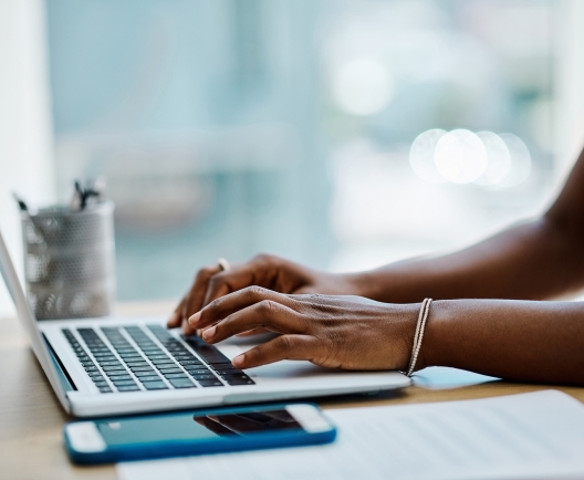 Closeup of a black businesswoman typing on a laptop keyboard in an office alone