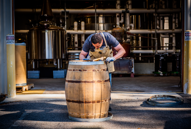 Man hunches over barrel outside diligently working