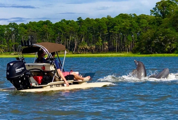Two guests on a small submersible watch dolphins play in front of them