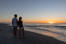 couple standing on the beach at sunrise