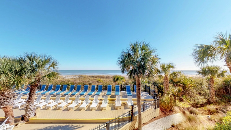 Long exposure of patio area with loungers with the beach and ocean as backdrop