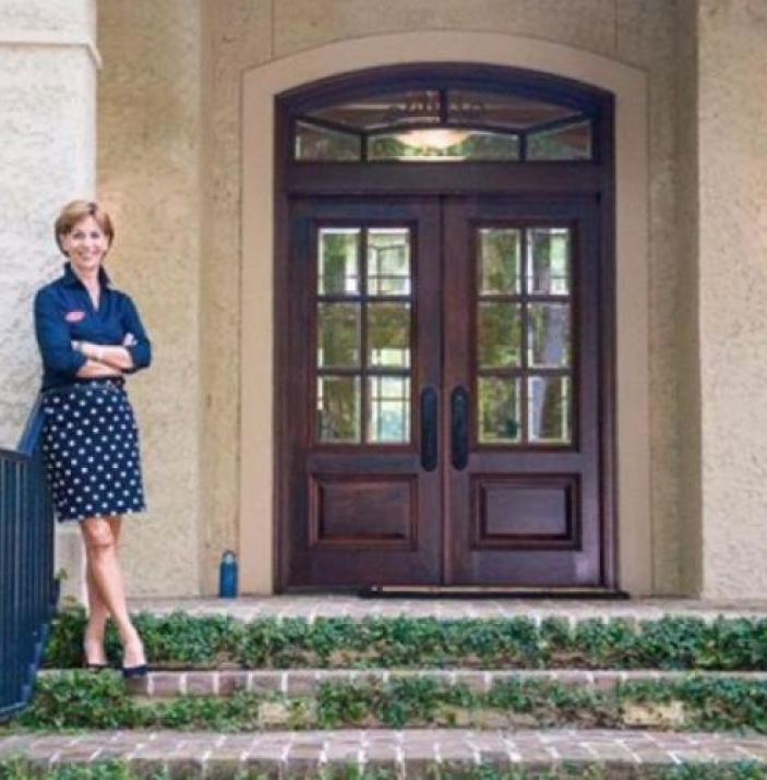 A woman poses outside of a residence